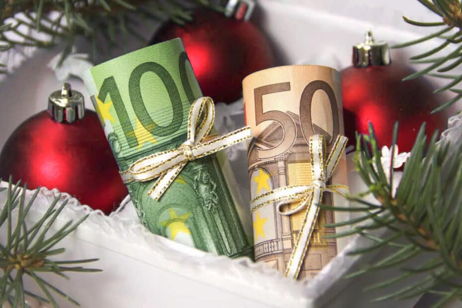 rote Weihnachtskugeln mit zusammengerollten Geldgeschenk 150 Euro als Weihnachtsbonus für Bürgergeld