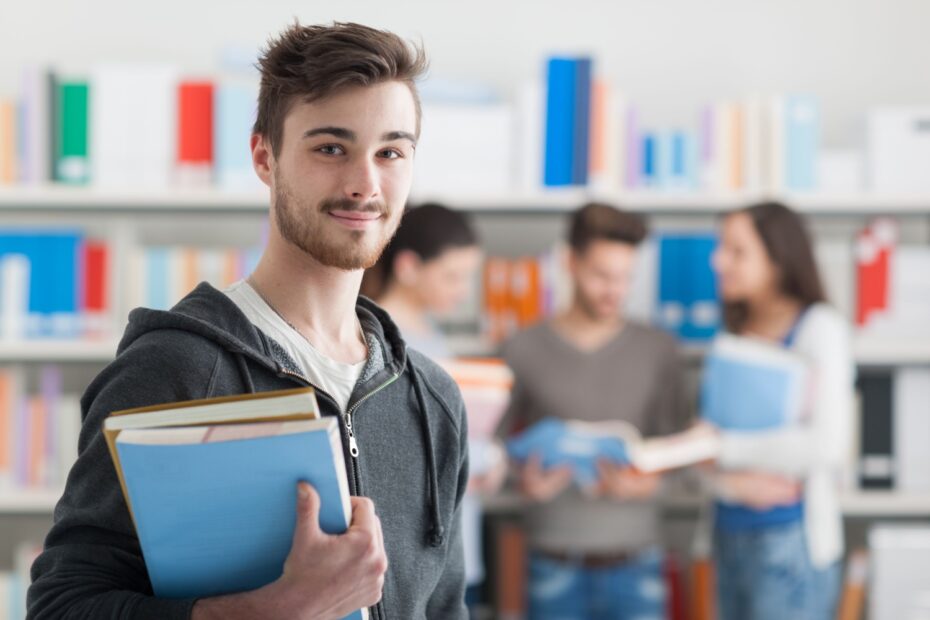 Student mit Arbeitsmaterialien in der Hand