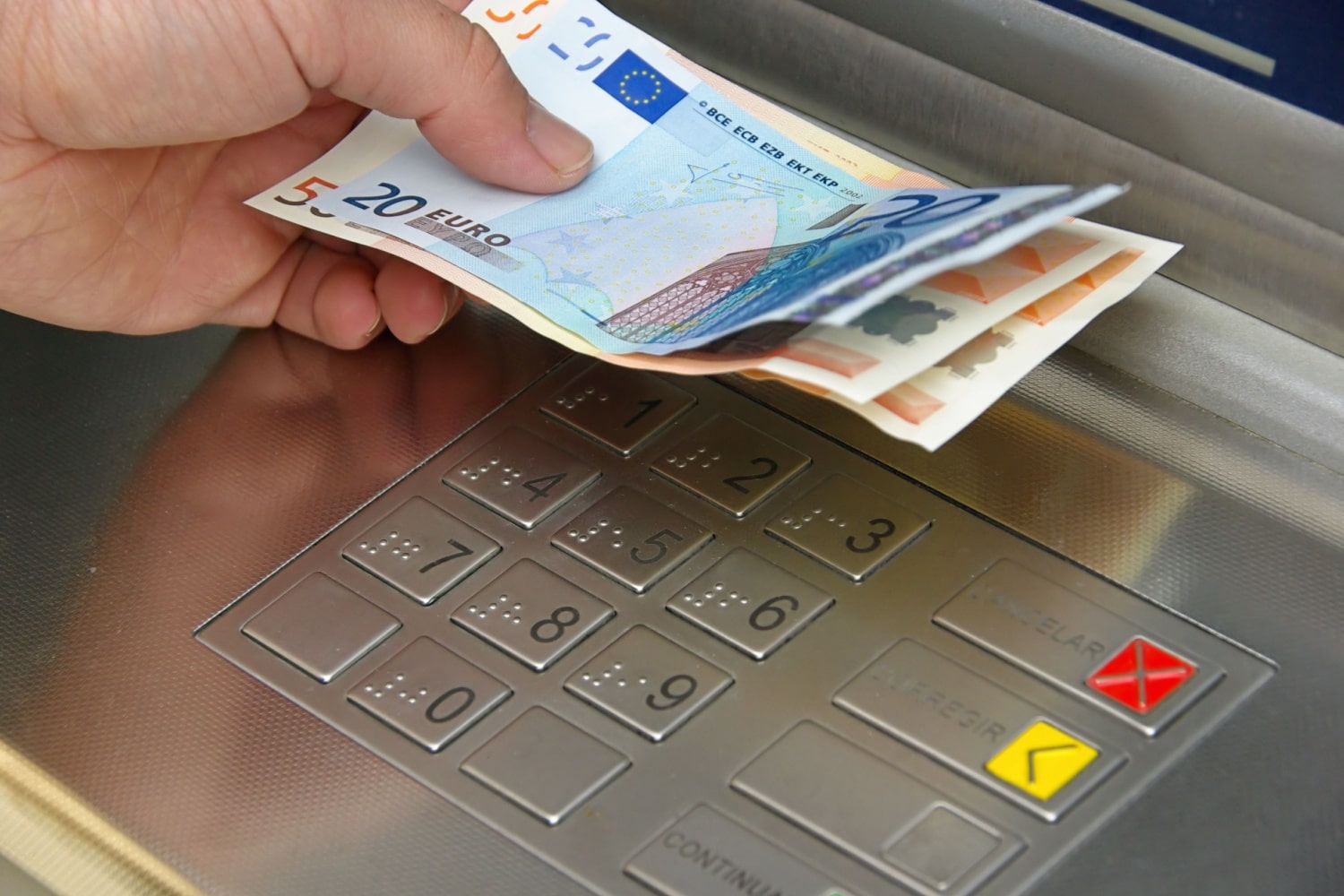 Hände heben Bargeld am Geldautomaten ab