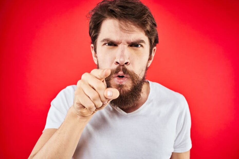 Wütender Mann vor rotem Hintergrund zeigt mit dem Finger