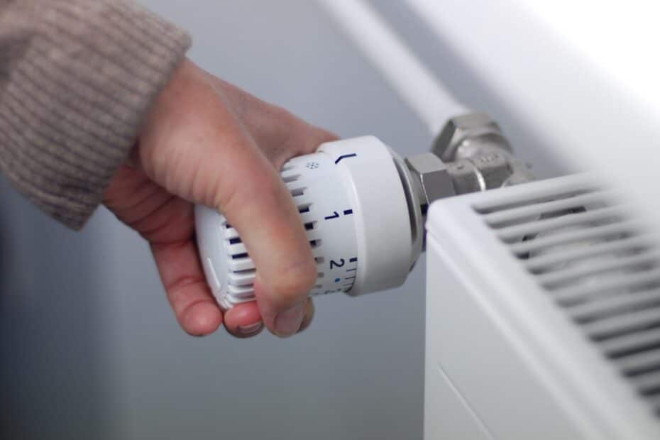 Weibliche Hand stellt Thermostat am Heizkörper ein