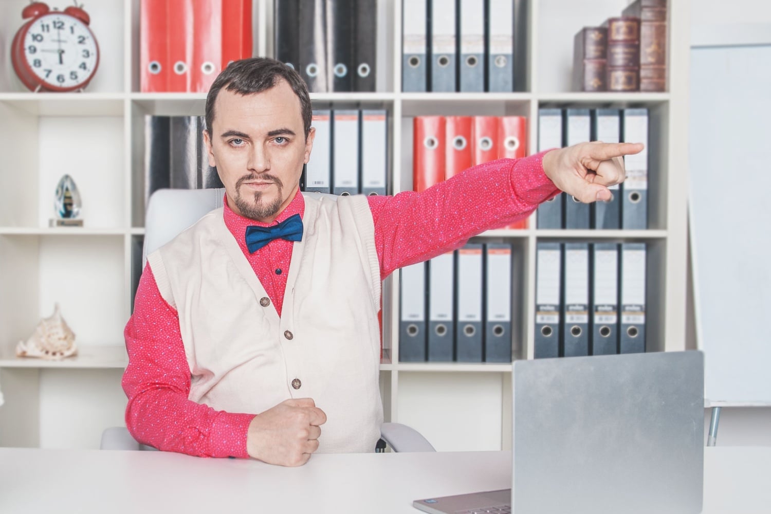 Mann am Schreibtisch zeigt mit dem Finger zur Tür, symbolisiert Ablehnung