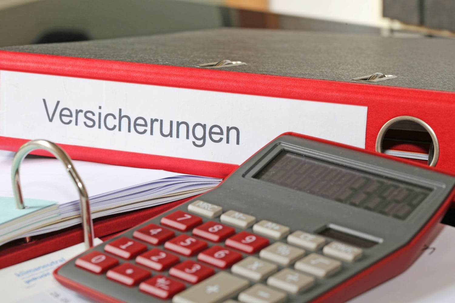 Taschenrechner vor Ordner mit Aufschrift Versicherungen