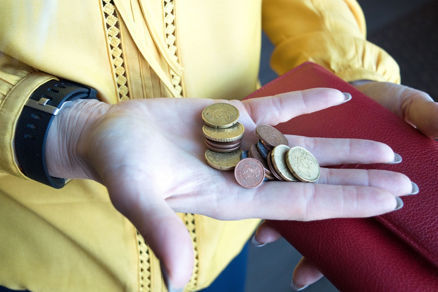 Frau hält Geldbörse und Kleingeld in der Hand.