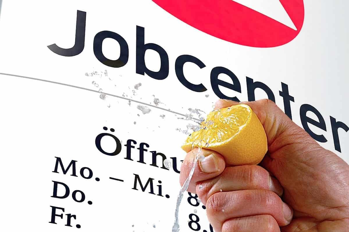 Hand presst Zitrone aus vor Jobcenter Schild